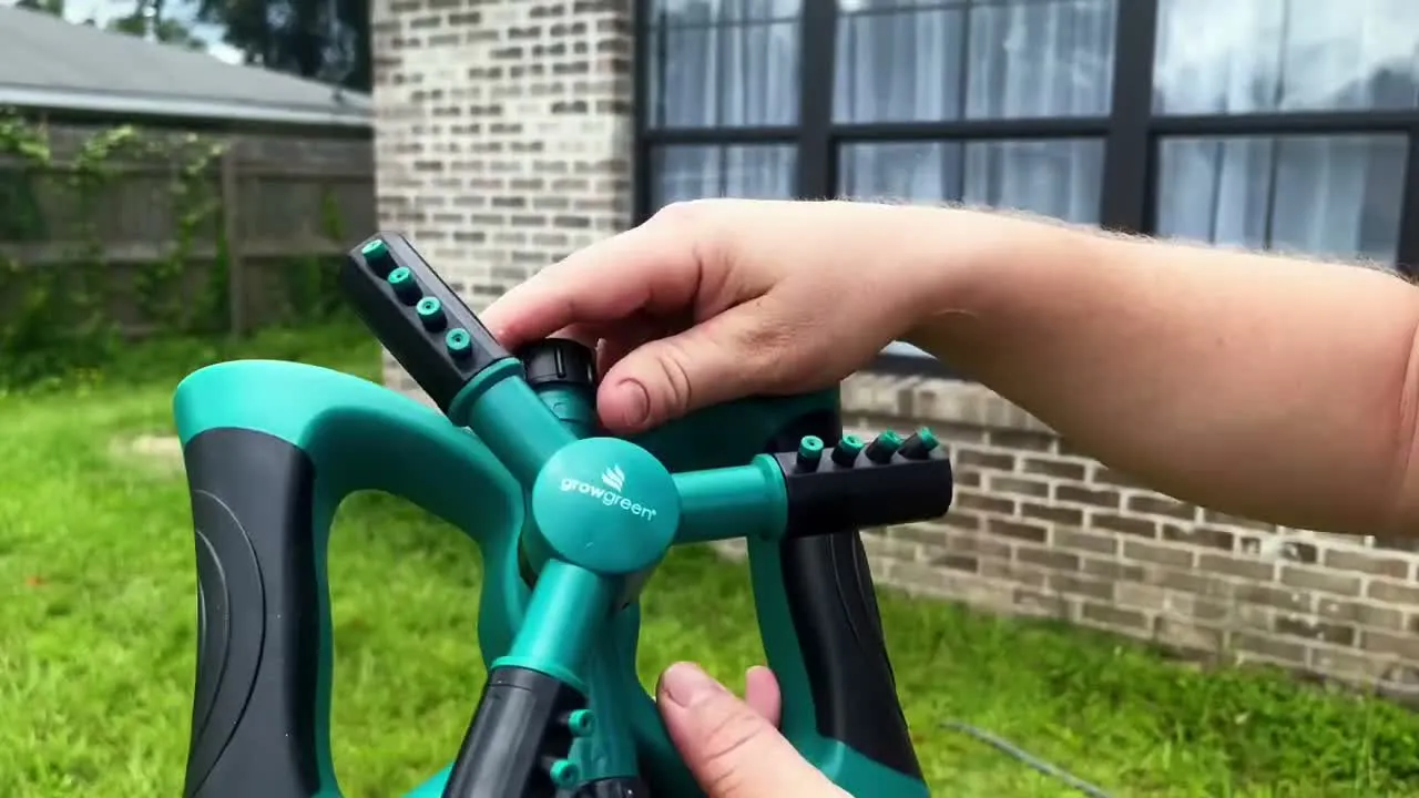 Hands adjusting the sprinkler arms in a real front yard